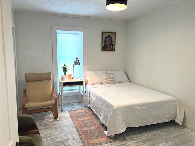 bedroom featuring wood finished floors and crown molding