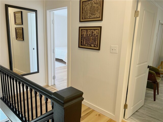 corridor featuring light wood finished floors and baseboards
