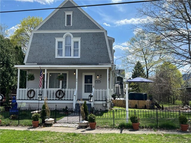view of front of property featuring a fenced front yard, a gambrel roof, a front yard, and covered porch