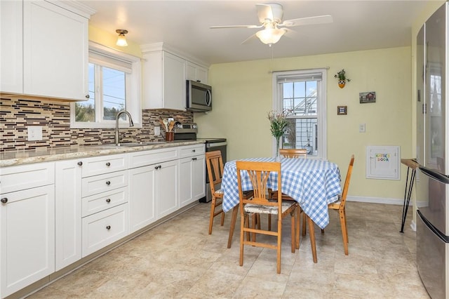 kitchen featuring tasteful backsplash, a sink, ceiling fan, white cabinets, and appliances with stainless steel finishes