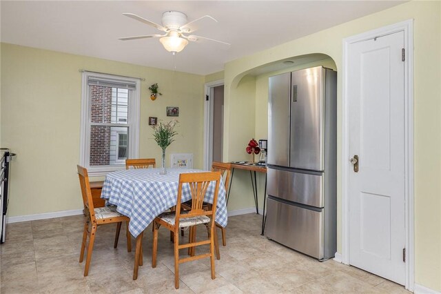 dining area with baseboards, arched walkways, and ceiling fan