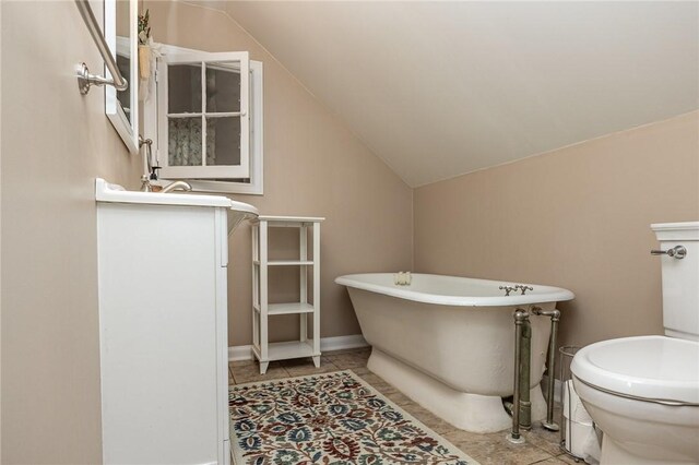 bathroom with tile patterned flooring, toilet, lofted ceiling, and a soaking tub
