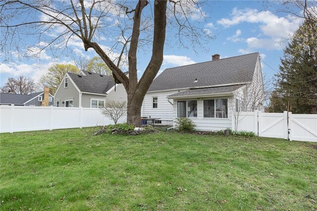 back of property with a gate, a lawn, a chimney, and a fenced backyard