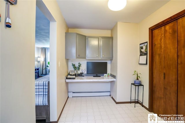 kitchen featuring baseboard heating, light floors, light countertops, baseboards, and gray cabinetry