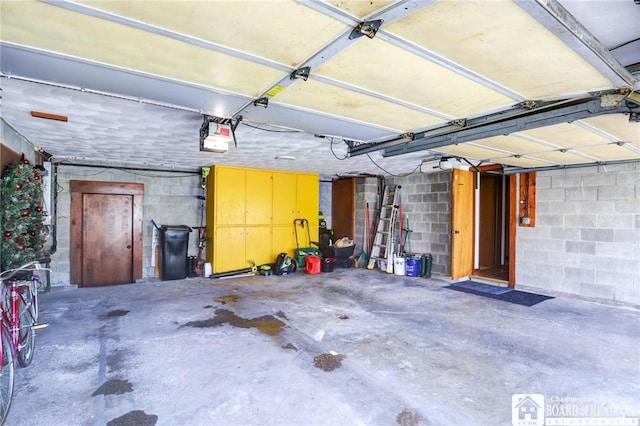 garage with a garage door opener and concrete block wall