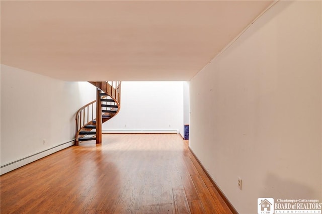 interior space with baseboards, baseboard heating, wood finished floors, and stairway