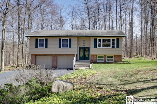 raised ranch with an attached garage, a front lawn, driveway, and brick siding