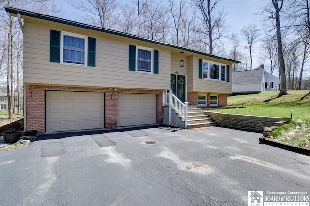 bi-level home featuring brick siding, a front lawn, aphalt driveway, and a garage