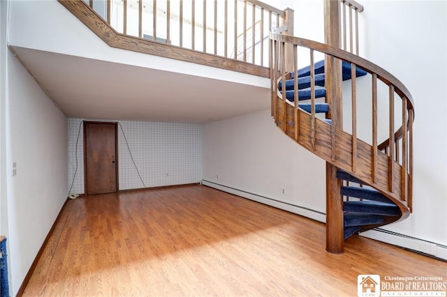 stairs with a baseboard radiator, baseboards, and wood finished floors