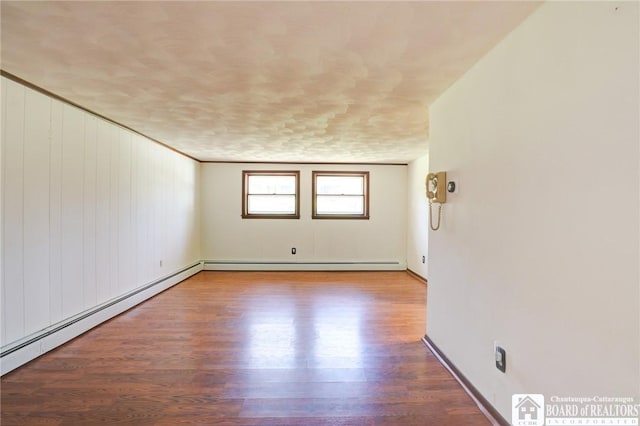 unfurnished room featuring a baseboard radiator, baseboards, and wood finished floors