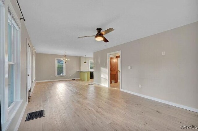 269 S Main St, Wellsville, NY 14895 - unfurnished living room featuring light wood-style floors, visible vents, baseboards, and ceiling fan with notable chandelier
