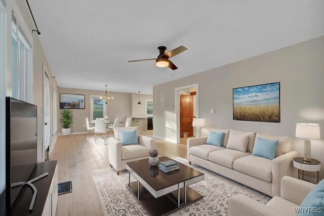 269 S Main St, Wellsville, NY 14895 - living area featuring light wood-type flooring, visible vents, baseboards, and ceiling fan with notable chandelier