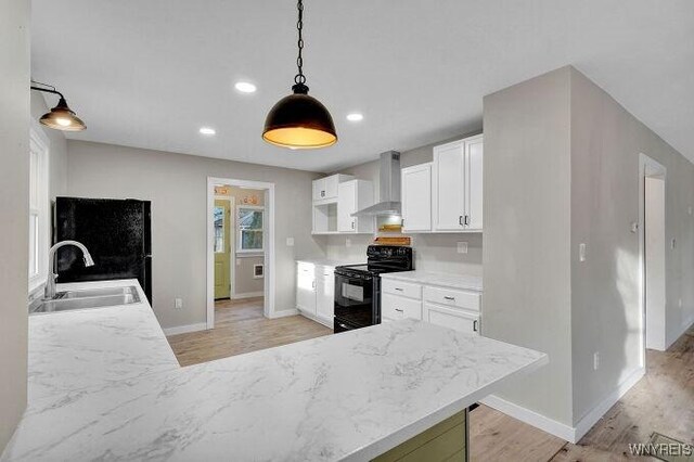 269 S Main St, Wellsville, NY 14895 - kitchen with black range with electric cooktop, wall chimney range hood, light wood finished floors, and a sink