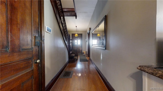corridor with baseboards, visible vents, stairway, and dark wood finished floors
