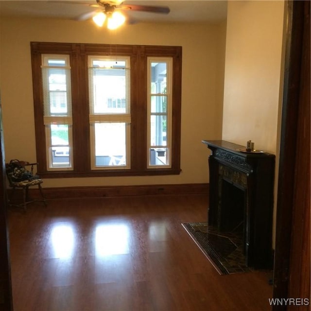 unfurnished living room featuring baseboards, a ceiling fan, wood finished floors, and a fireplace