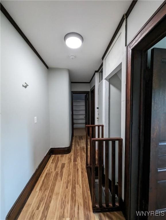 hallway with light wood-type flooring, baseboards, and an upstairs landing