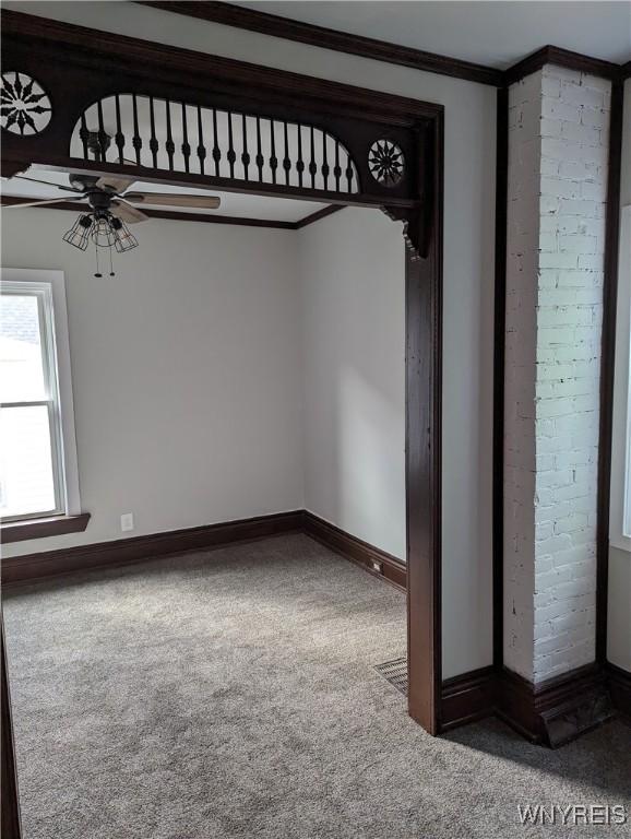 empty room with a ceiling fan, baseboards, carpet, and crown molding