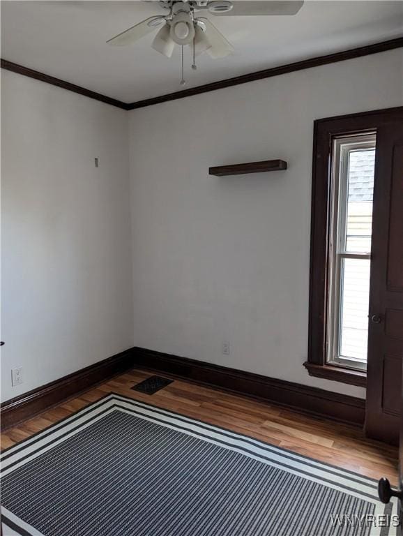 spare room featuring ornamental molding, baseboards, a ceiling fan, and wood finished floors