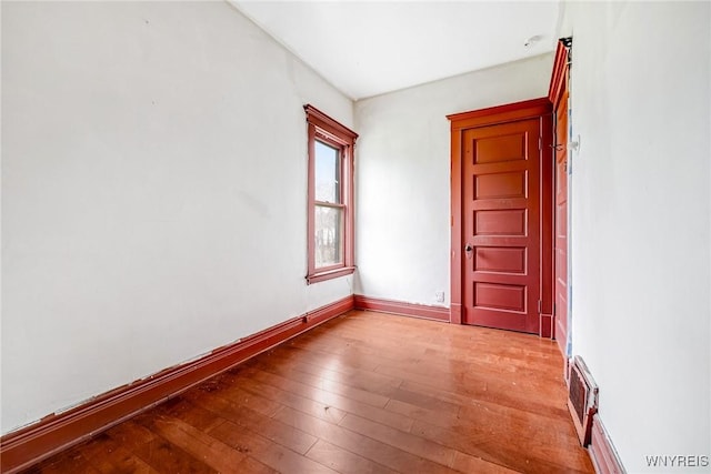 spare room featuring hardwood / wood-style floors, visible vents, and baseboards