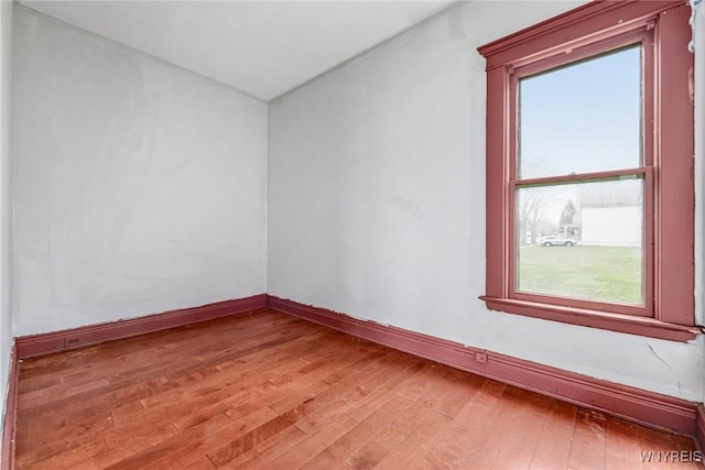 spare room featuring light wood finished floors, baseboards, and a healthy amount of sunlight