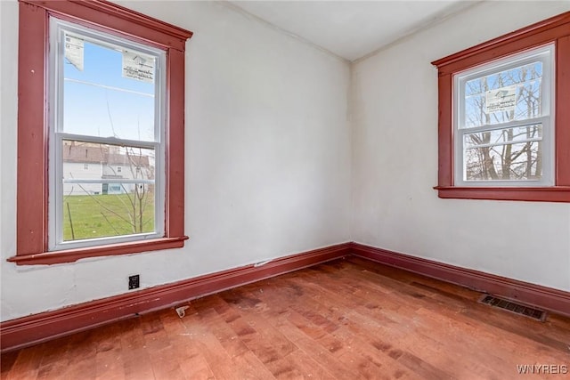 spare room featuring baseboards, wood finished floors, and visible vents