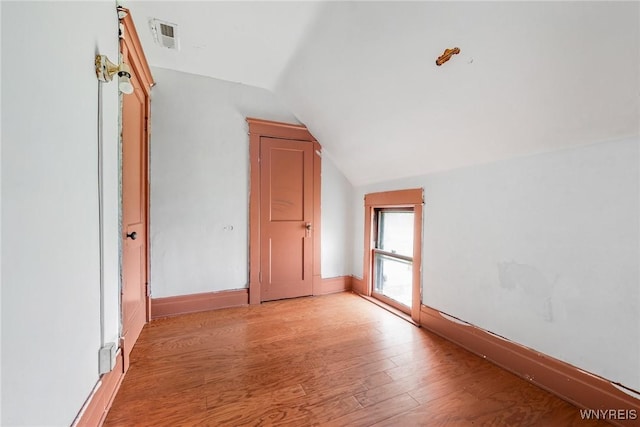 bonus room with visible vents, vaulted ceiling, baseboards, and light wood-style flooring