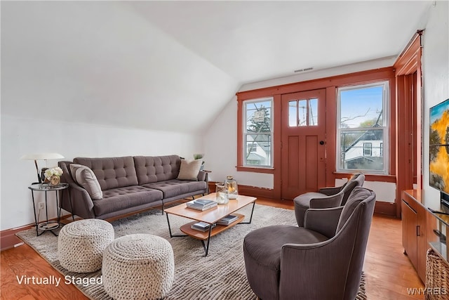 living area with lofted ceiling, baseboards, visible vents, and light wood-style floors