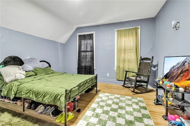 bedroom with vaulted ceiling and wood finished floors
