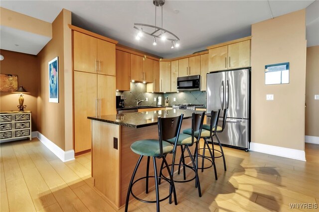 132 Lakefront Blvd Unit 504, Buffalo, NY 14202 - kitchen featuring light wood finished floors, baseboards, freestanding refrigerator, a kitchen island, and a breakfast bar area