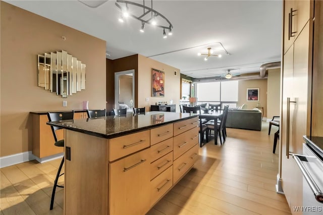 132 Lakefront Blvd Unit 504, Buffalo, NY 14202 - kitchen with light brown cabinetry, a breakfast bar, a kitchen island, open floor plan, and ceiling fan
