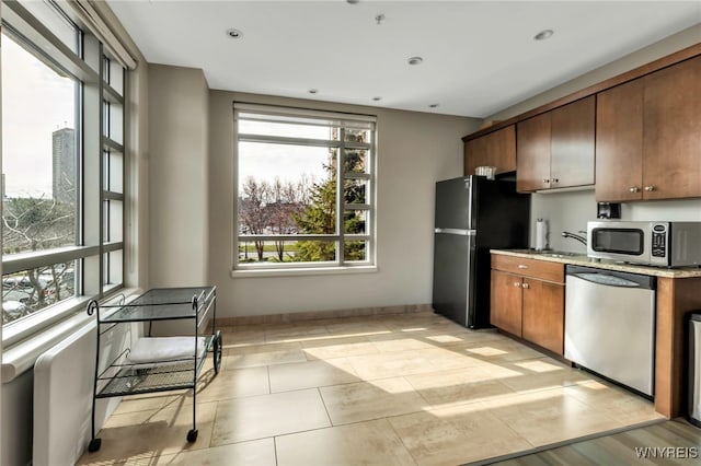 132 Lakefront Blvd Unit 504, Buffalo, NY 14202 - kitchen featuring light tile patterned floors, plenty of natural light, baseboards, and appliances with stainless steel finishes