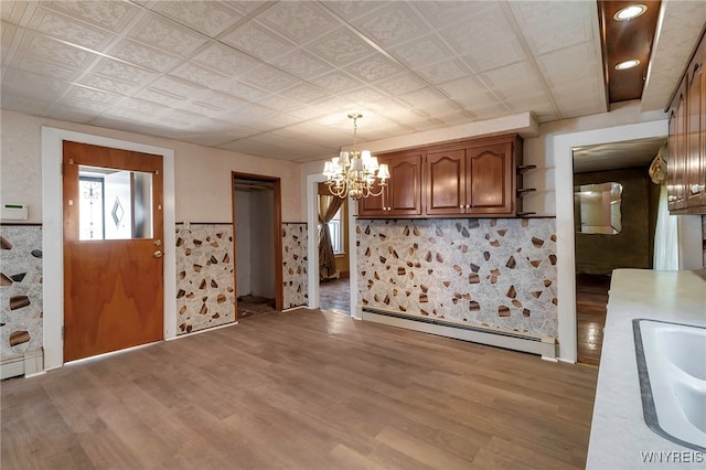 foyer with baseboard heating, a wainscoted wall, a chandelier, and light wood-style floors