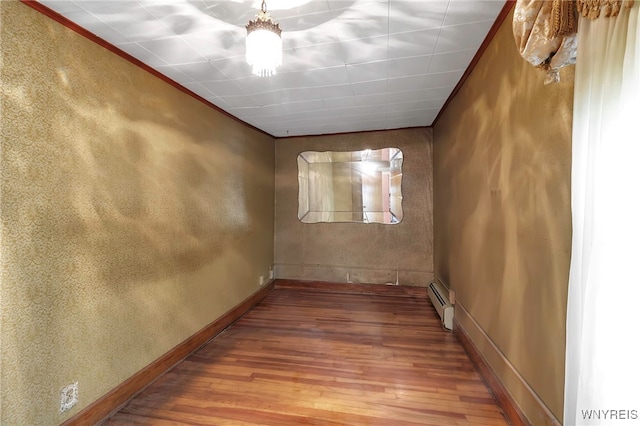 unfurnished room featuring crown molding, baseboard heating, baseboards, and wood-type flooring