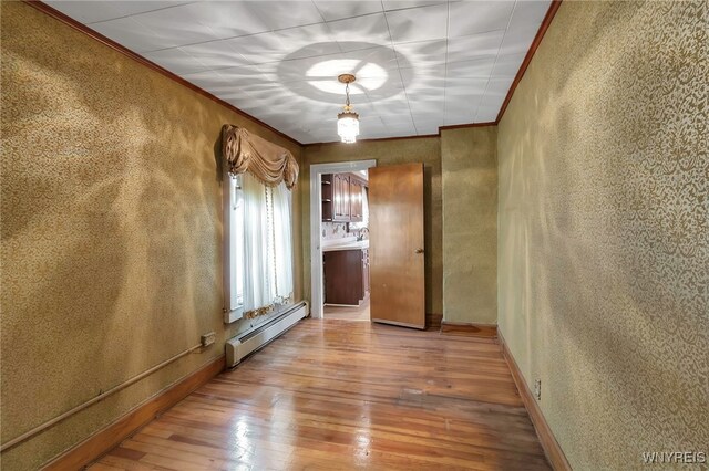 unfurnished room featuring a baseboard heating unit, a textured wall, wood-type flooring, and crown molding