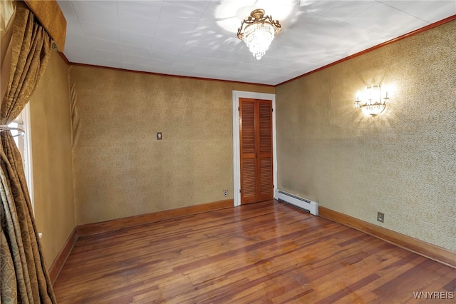 unfurnished room featuring a baseboard radiator, wood finished floors, and crown molding