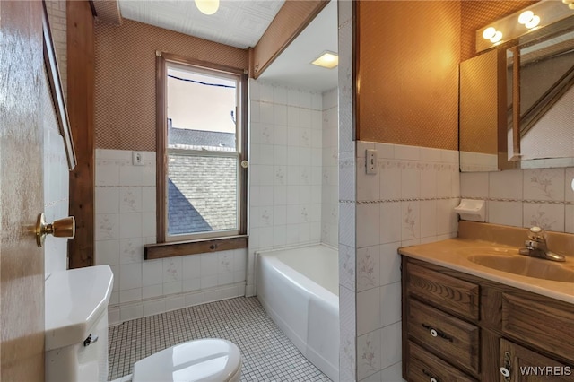 bathroom with vanity, toilet, a tub to relax in, and tile walls