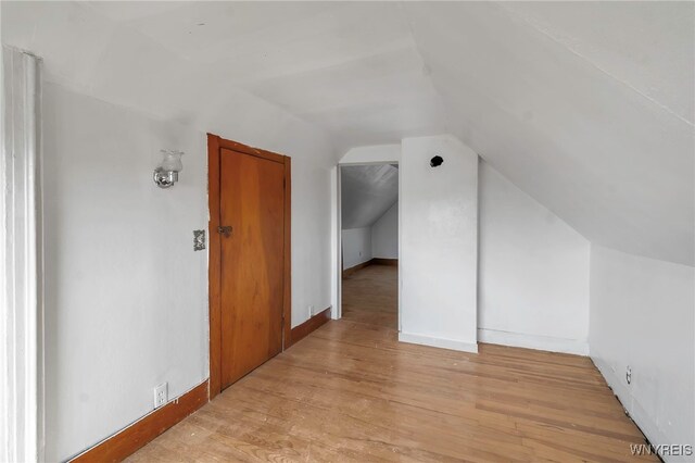 bonus room with lofted ceiling, baseboards, and light wood finished floors