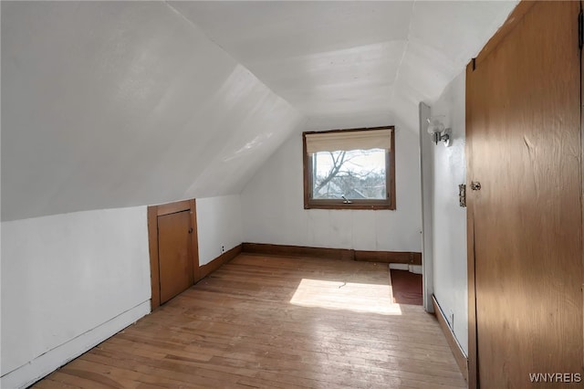 additional living space with light wood finished floors, vaulted ceiling, and baseboards
