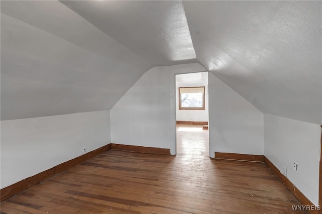 bonus room featuring lofted ceiling, hardwood / wood-style flooring, and baseboards