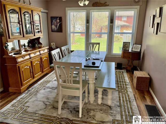 dining space with wood finished floors, visible vents, and baseboards