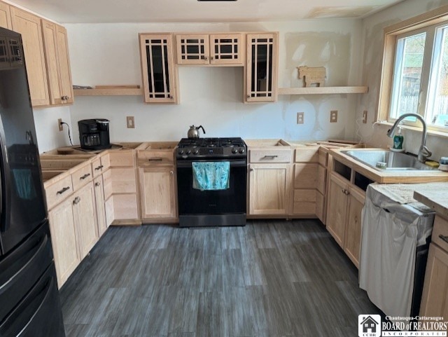 kitchen with range with gas stovetop, a sink, black refrigerator, open shelves, and light brown cabinetry