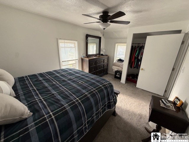 bedroom featuring a ceiling fan, a textured ceiling, multiple windows, and carpet flooring