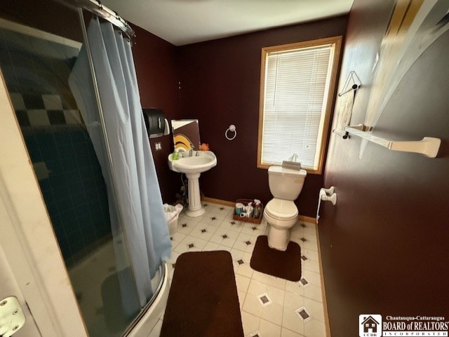 bathroom with toilet, a shower stall, and baseboards