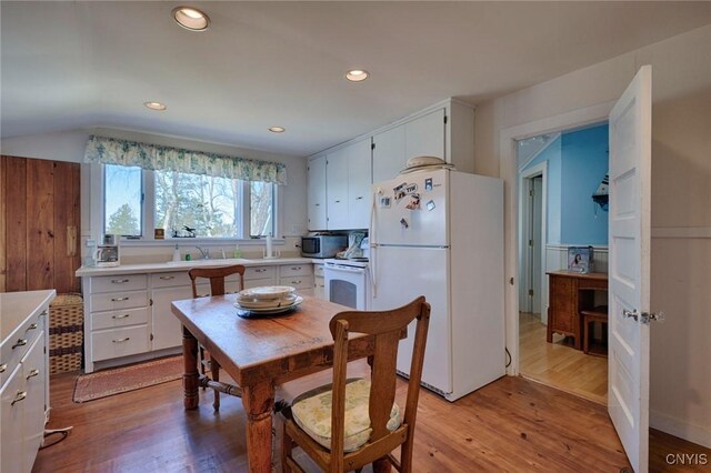 kitchen featuring light countertops, light wood-style flooring, white cabinets, and white appliances