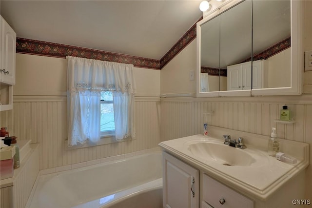 full bath with vaulted ceiling, a bath, a decorative wall, and vanity