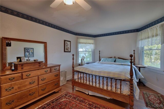 bedroom with baseboards, light wood-style floors, and multiple windows