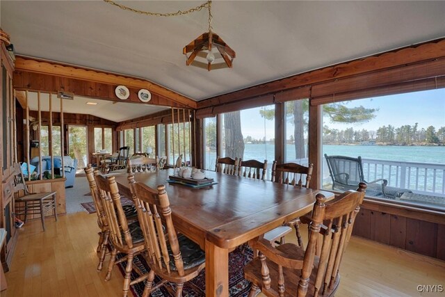 dining space with lofted ceiling, a water view, and light wood-style flooring