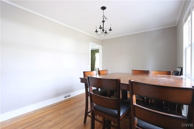 dining area with baseboards, wood finished floors, visible vents, and ornamental molding