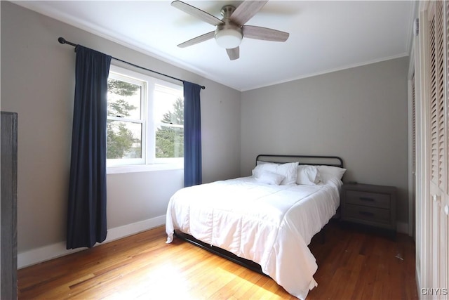 bedroom with ornamental molding, a ceiling fan, wood finished floors, and baseboards