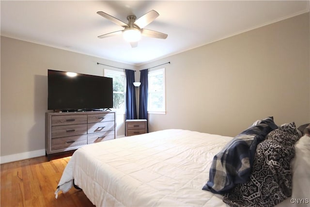bedroom featuring baseboards, wood finished floors, a ceiling fan, and ornamental molding